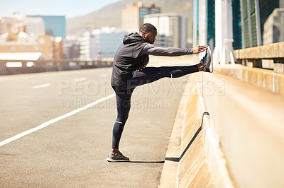 Buy stock photo Shot of a sporty young man stretching before his run