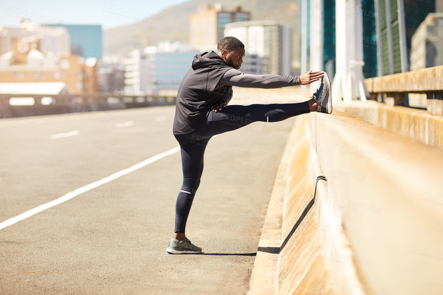 Buy stock photo Shot of a sporty young man stretching before his run