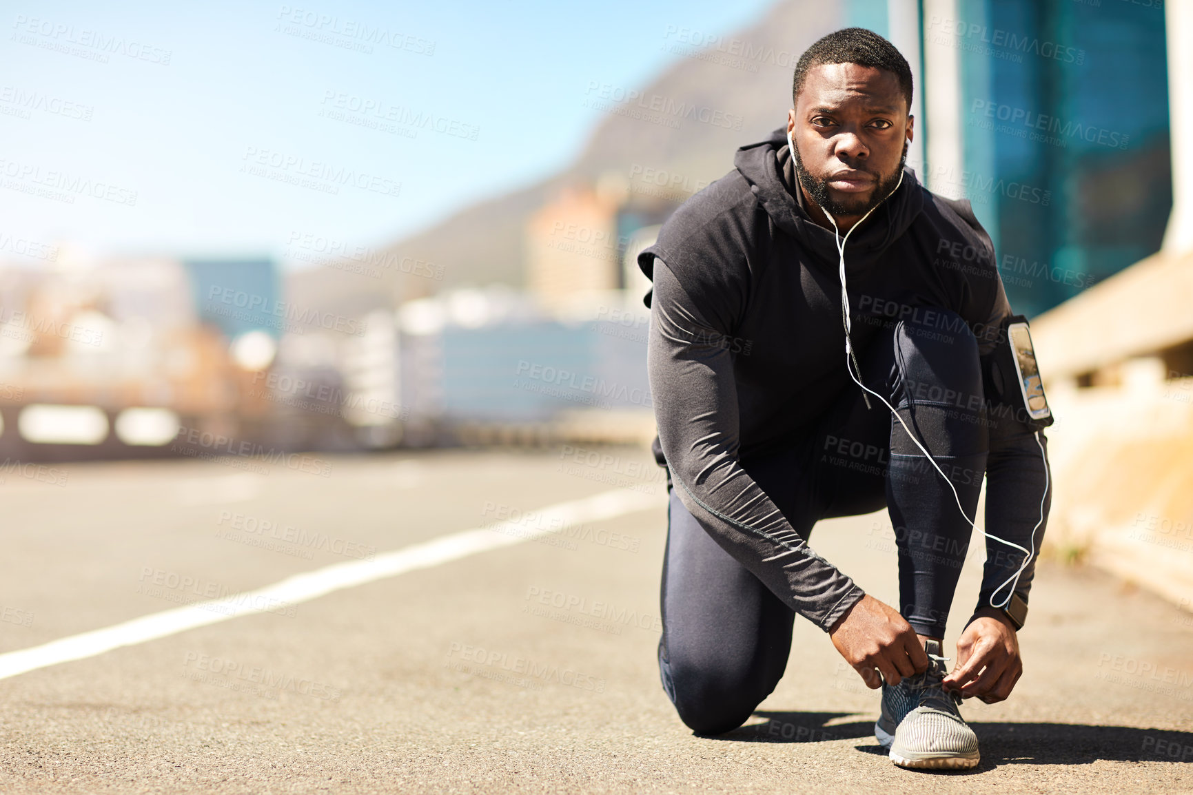 Buy stock photo Shot of a sporty young man tying his shoelaces while out for a run