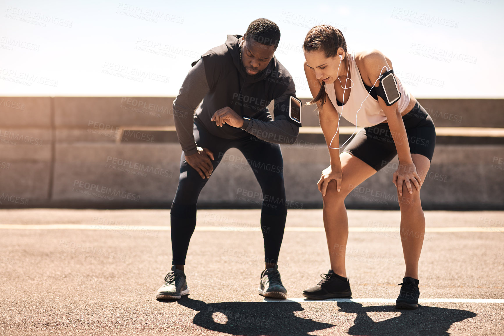Buy stock photo Shot of two sporty young people checking the stopwatch after a run