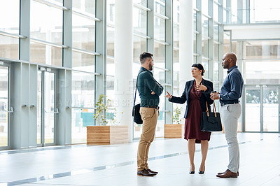 Buy stock photo Full length shot of three business colleagues talking while standing in their office