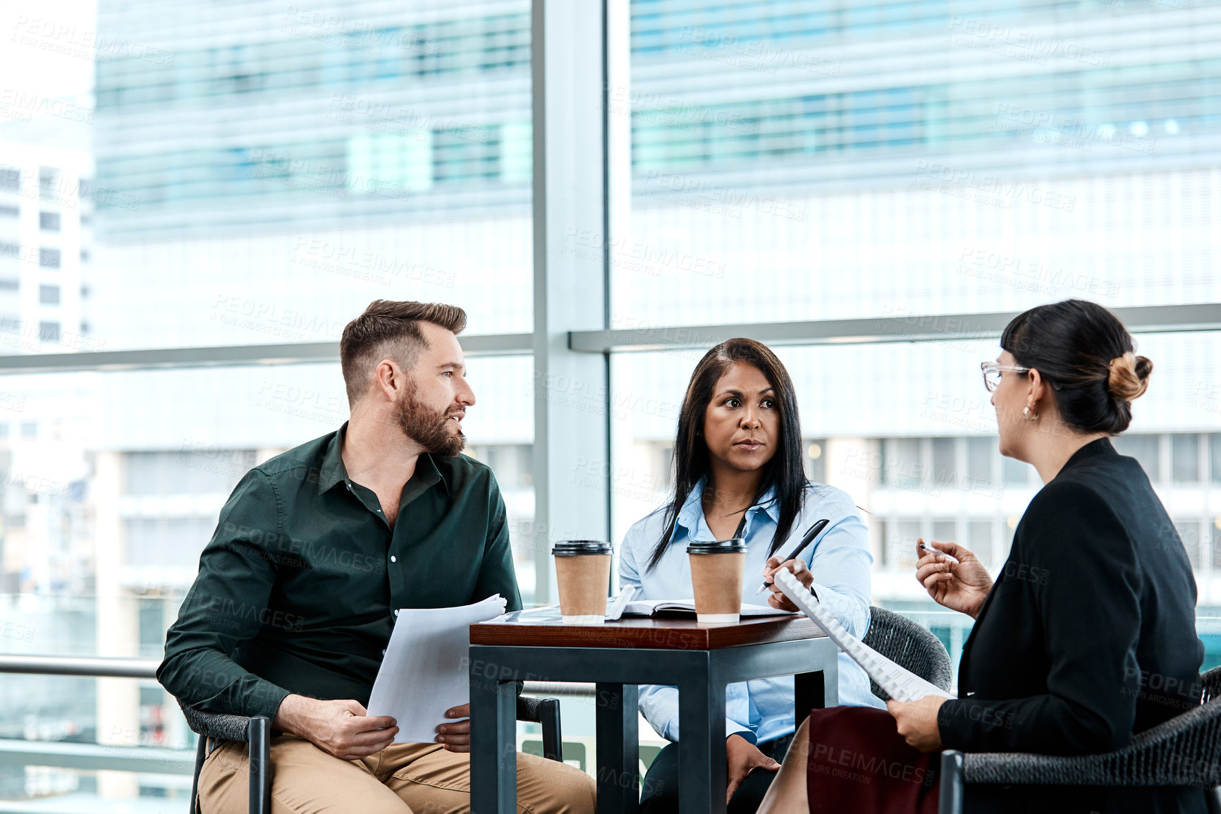 Buy stock photo Cropped shot of three business colleagues having a discussion while sitting in their office