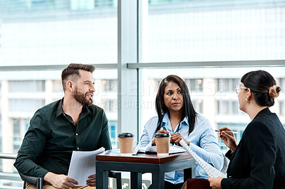Buy stock photo Cropped shot of three business colleagues having a discussion while sitting in their office