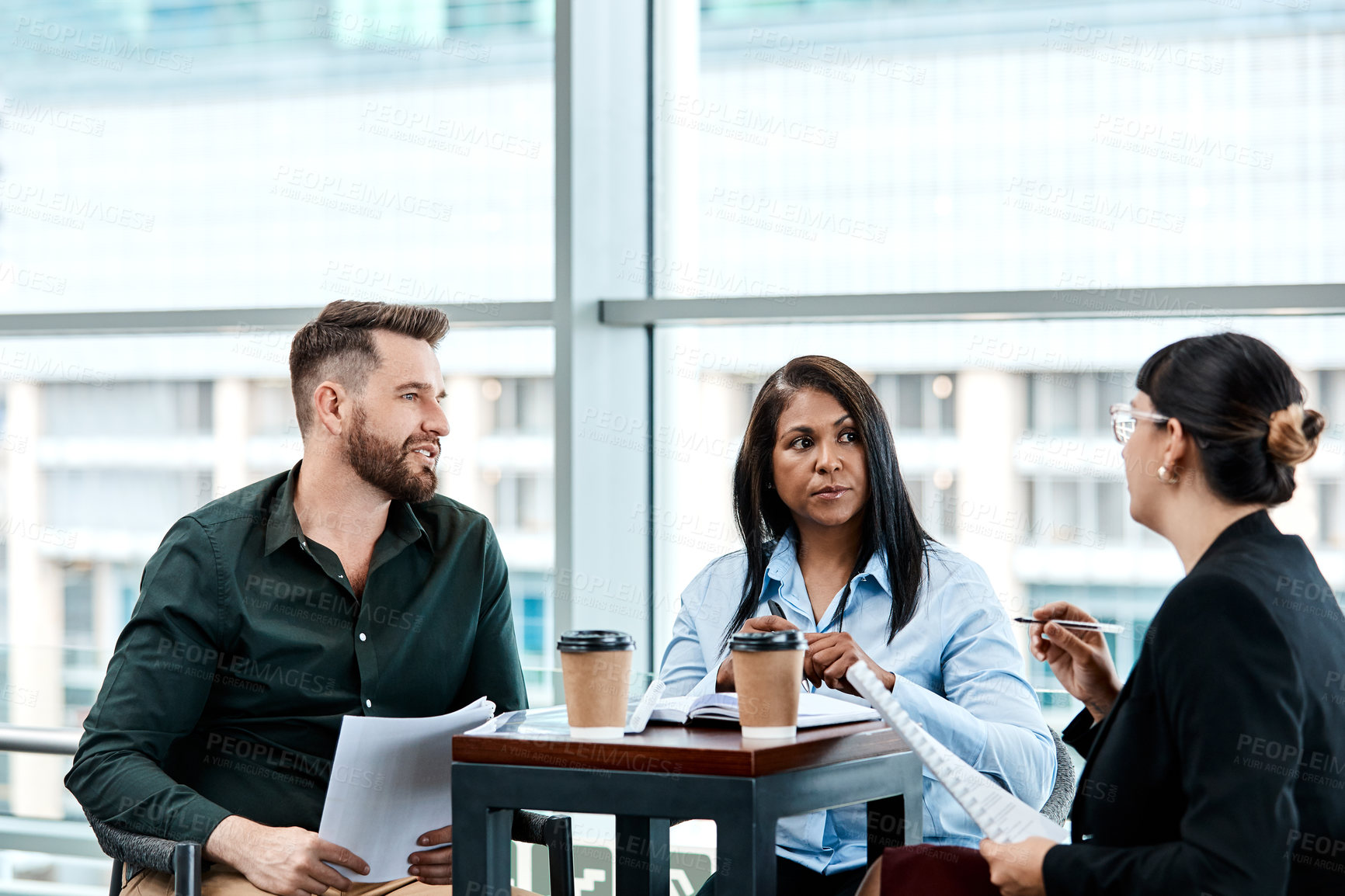 Buy stock photo Cropped shot of three business colleagues having a discussion while sitting in their office