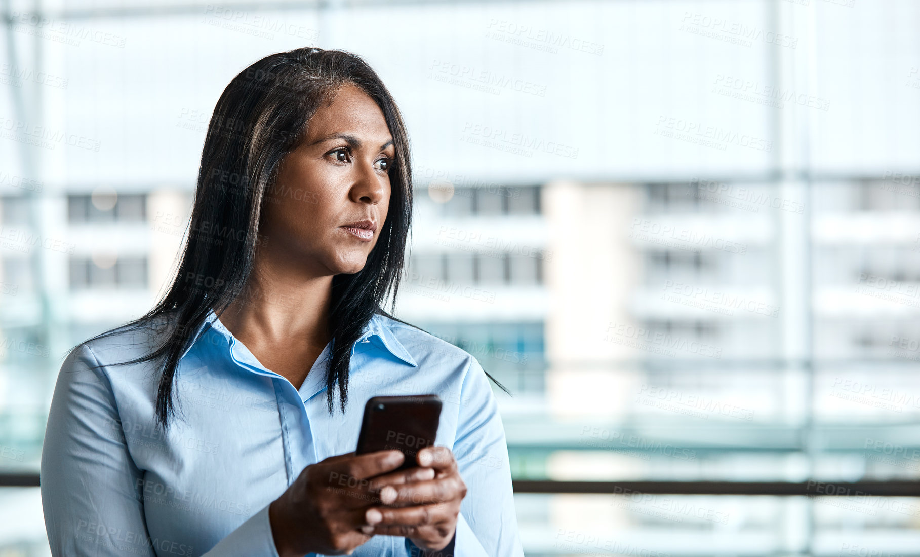 Buy stock photo Cropped shot of an attractive businesswoman texting while standing in her office
