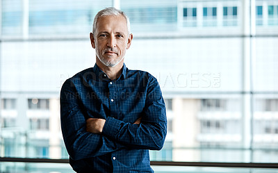 Buy stock photo Cropped portrait of a handsome businessman standing with his arms folded in the office