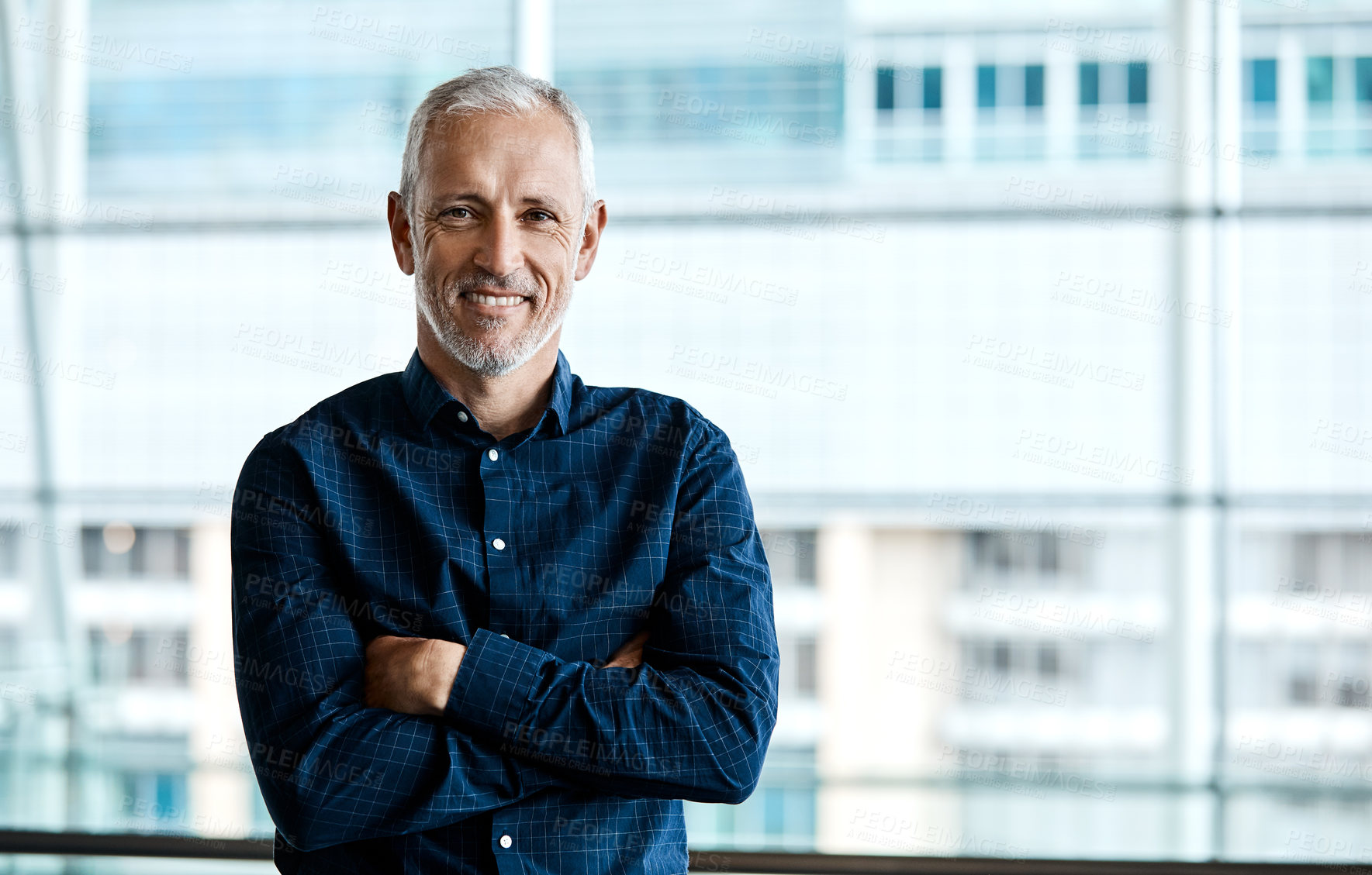 Buy stock photo Cropped portrait of a handsome businessman standing with his arms folded in the office