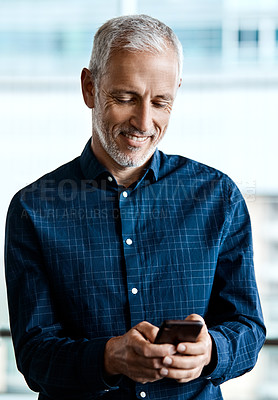 Buy stock photo Cropped shot of a handsome businessman texting while standing in his office