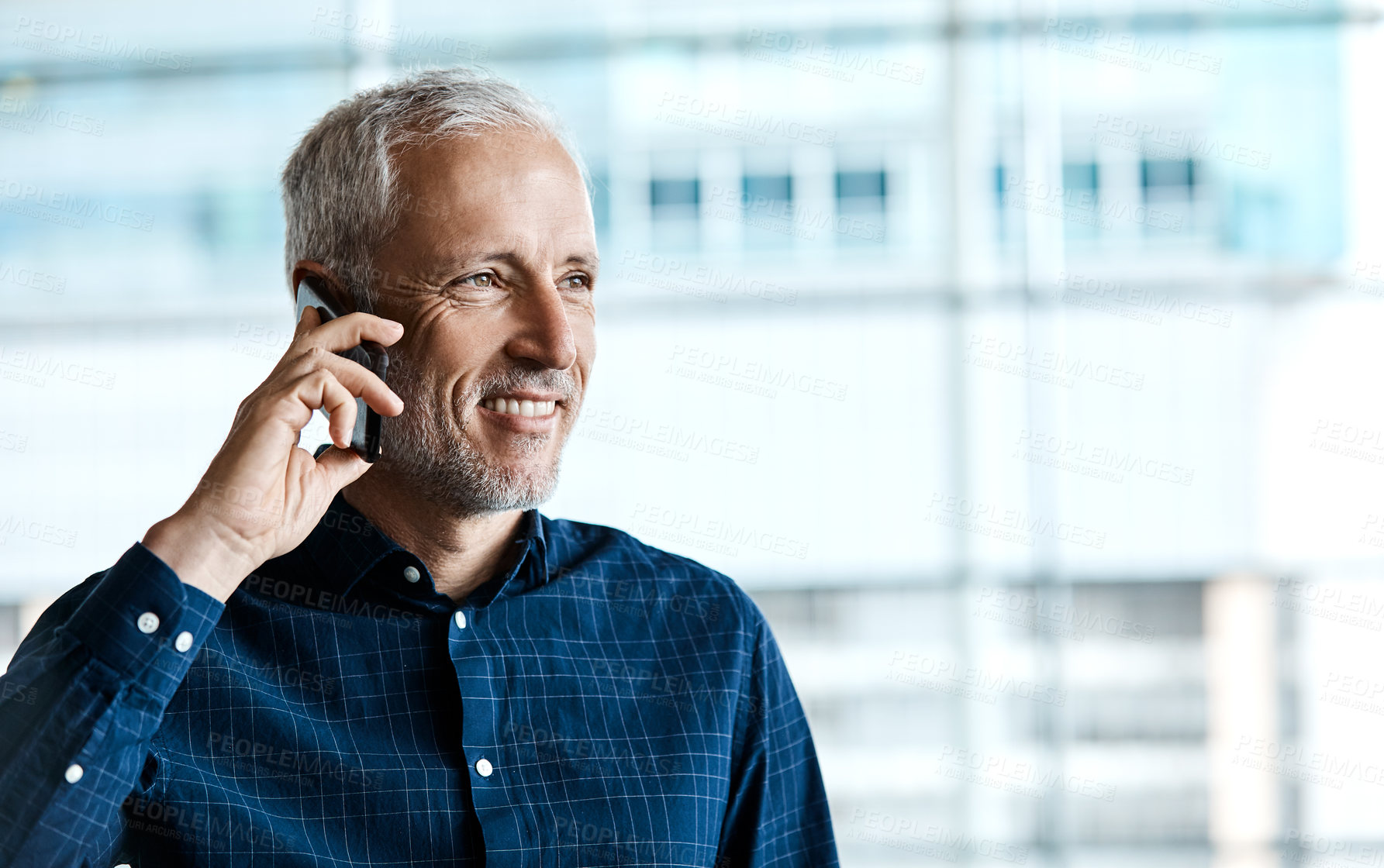 Buy stock photo Cropped shot of a handsome businessman making a phonecall while standing in his office