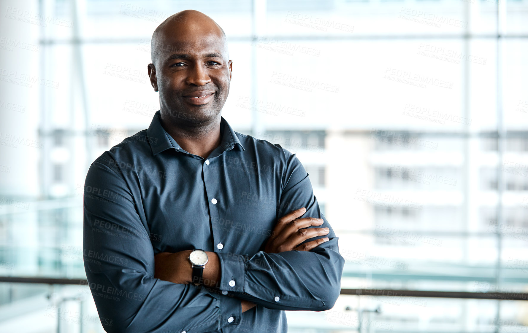 Buy stock photo Cropped portrait of a handsome businessman standing with his arms folded in the office