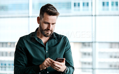 Buy stock photo Cropped shot of a handsome businessman texting while standing in his office