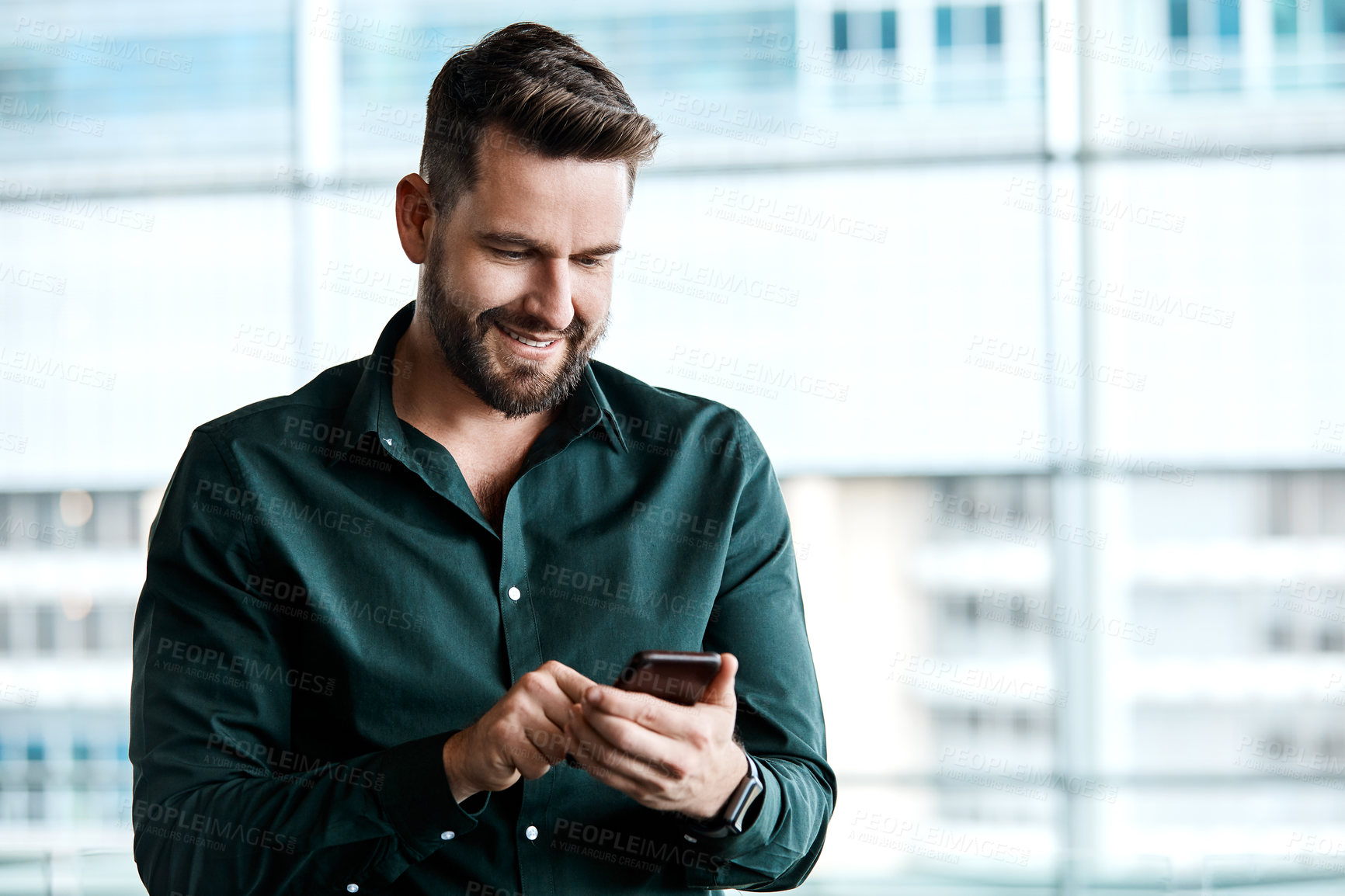 Buy stock photo Cropped shot of a handsome businessman texting while standing in his office