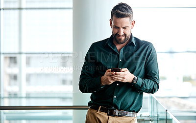 Buy stock photo Cropped shot of a handsome businessman texting while standing in his office