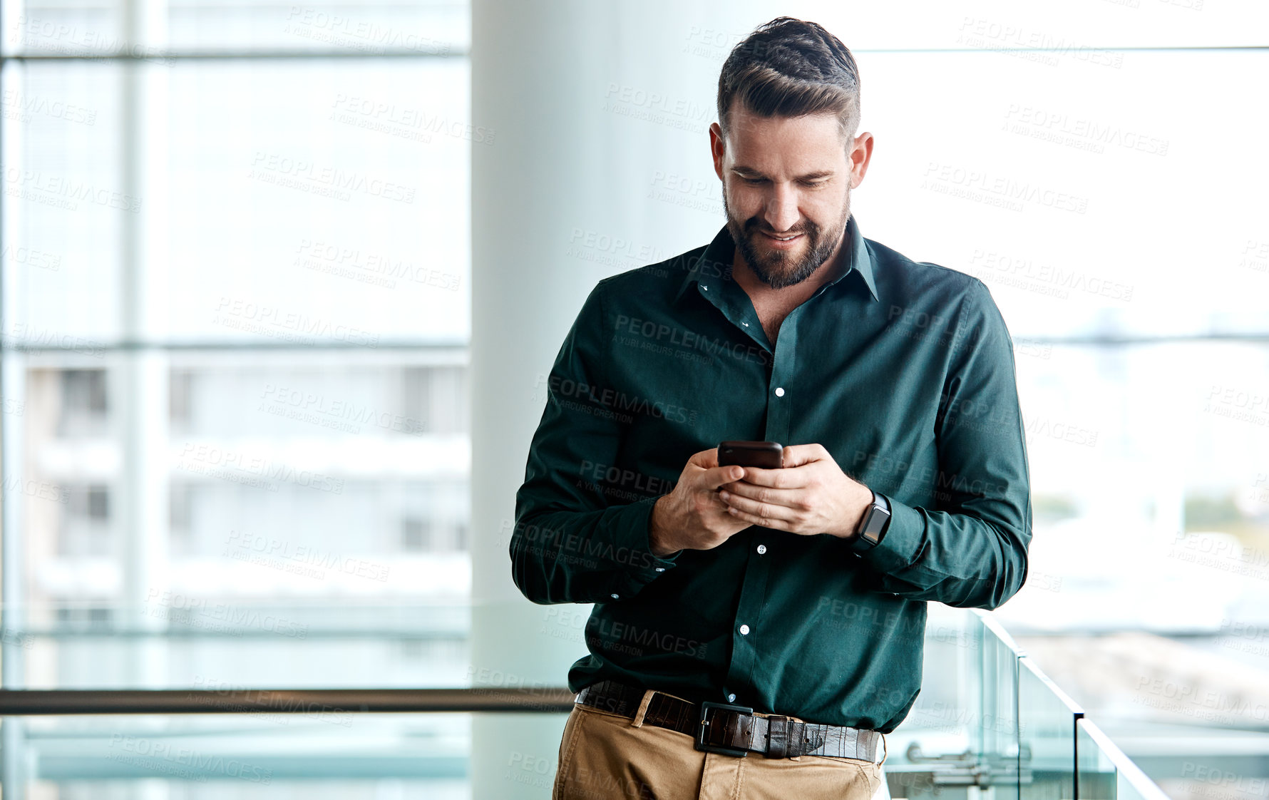 Buy stock photo Cropped shot of a handsome businessman texting while standing in his office