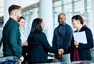 Buy stock photo Shot of two businesspeople shaking hands while their colleagues look on