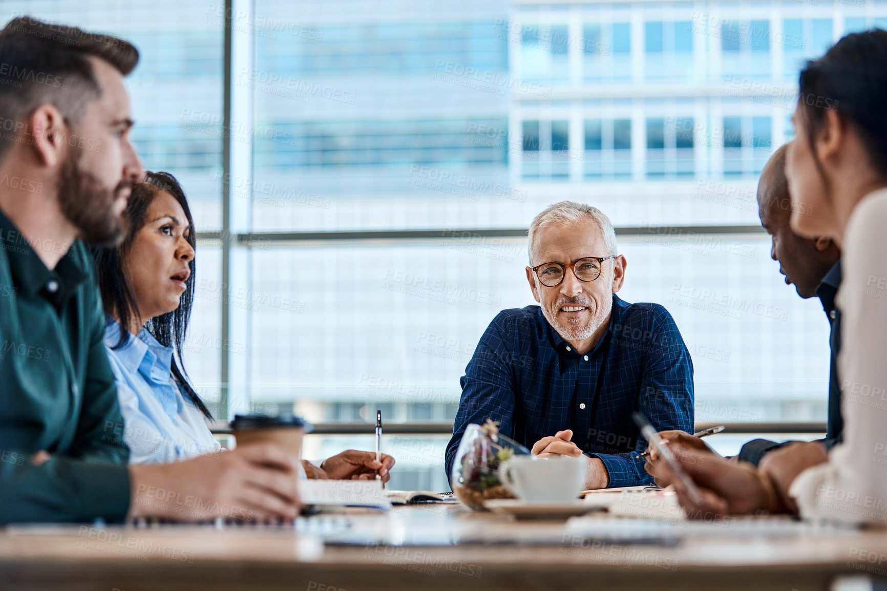 Buy stock photo Shot of a mature businessman discussing ideas with colleagues during a meeting at work