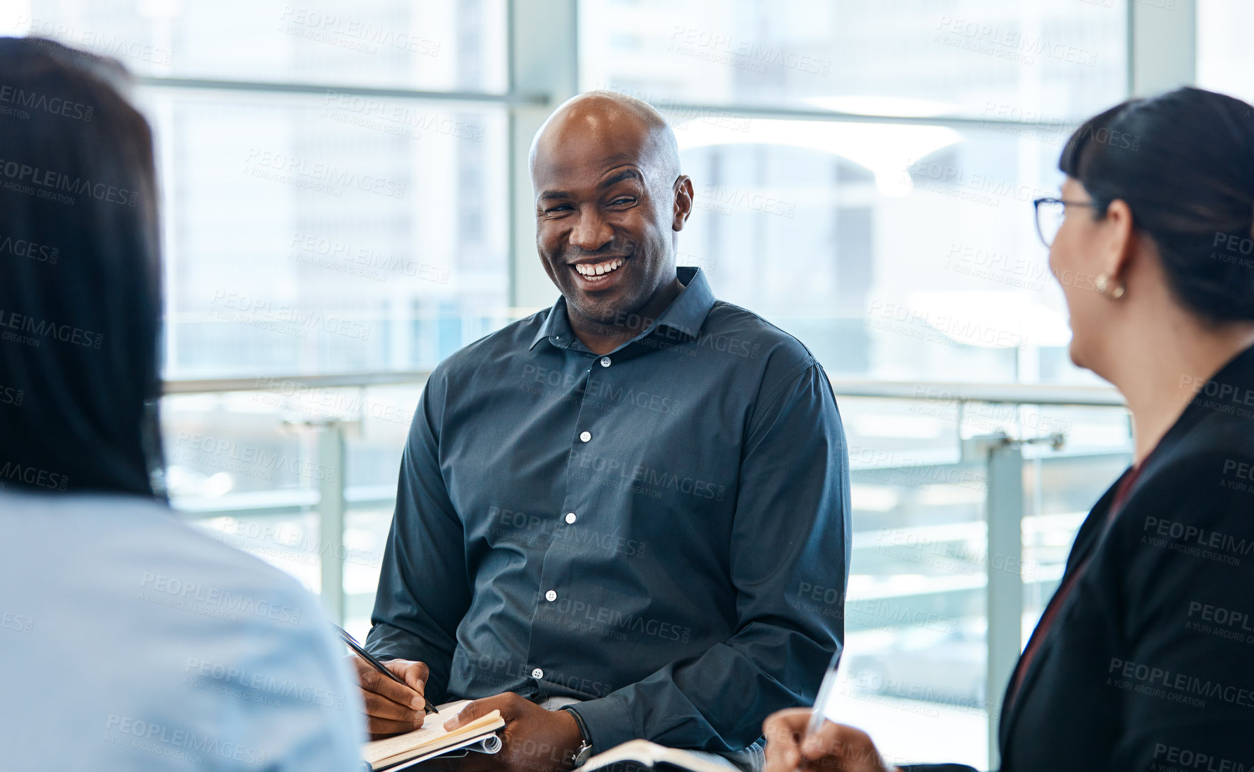 Buy stock photo Shot of a handsome businessman taking down notes during a meeting with colleagues at work