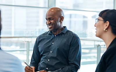 Buy stock photo Shot of a handsome businessman smiling during a meeting with colleagues at work