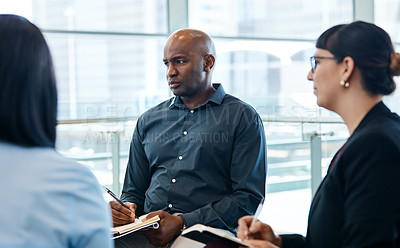 Buy stock photo Shot of a handsome businessman taking down notes during a meeting with colleagues at work