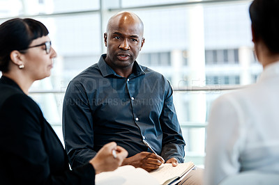 Buy stock photo Shot of a handsome businessman taking down notes during a meeting with colleagues at work