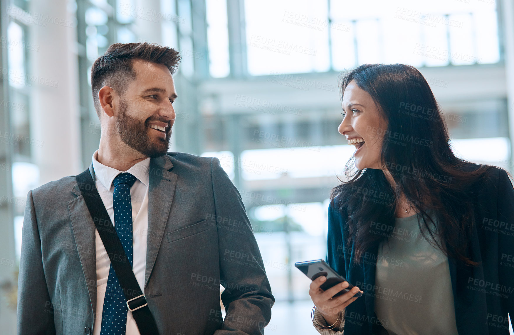 Buy stock photo Business people, laugh and walking with phone for travel, work trip and partnership in airport. Employee, terminal lobby and tech for international opportunity, social media or project collaboration