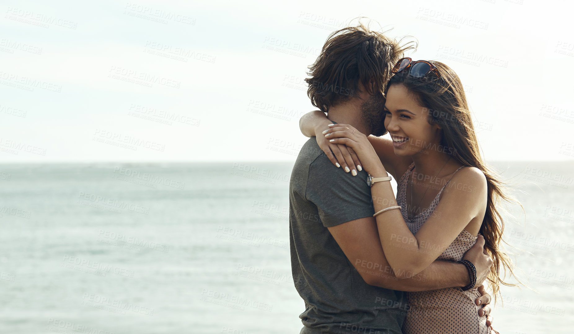 Buy stock photo Cropped shot of an affectionate young couple hugging each other while standing on the beach during a road trip