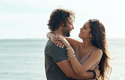Buy stock photo Cropped shot of an affectionate and happy young couple holding each other closely on the beach during a road trip