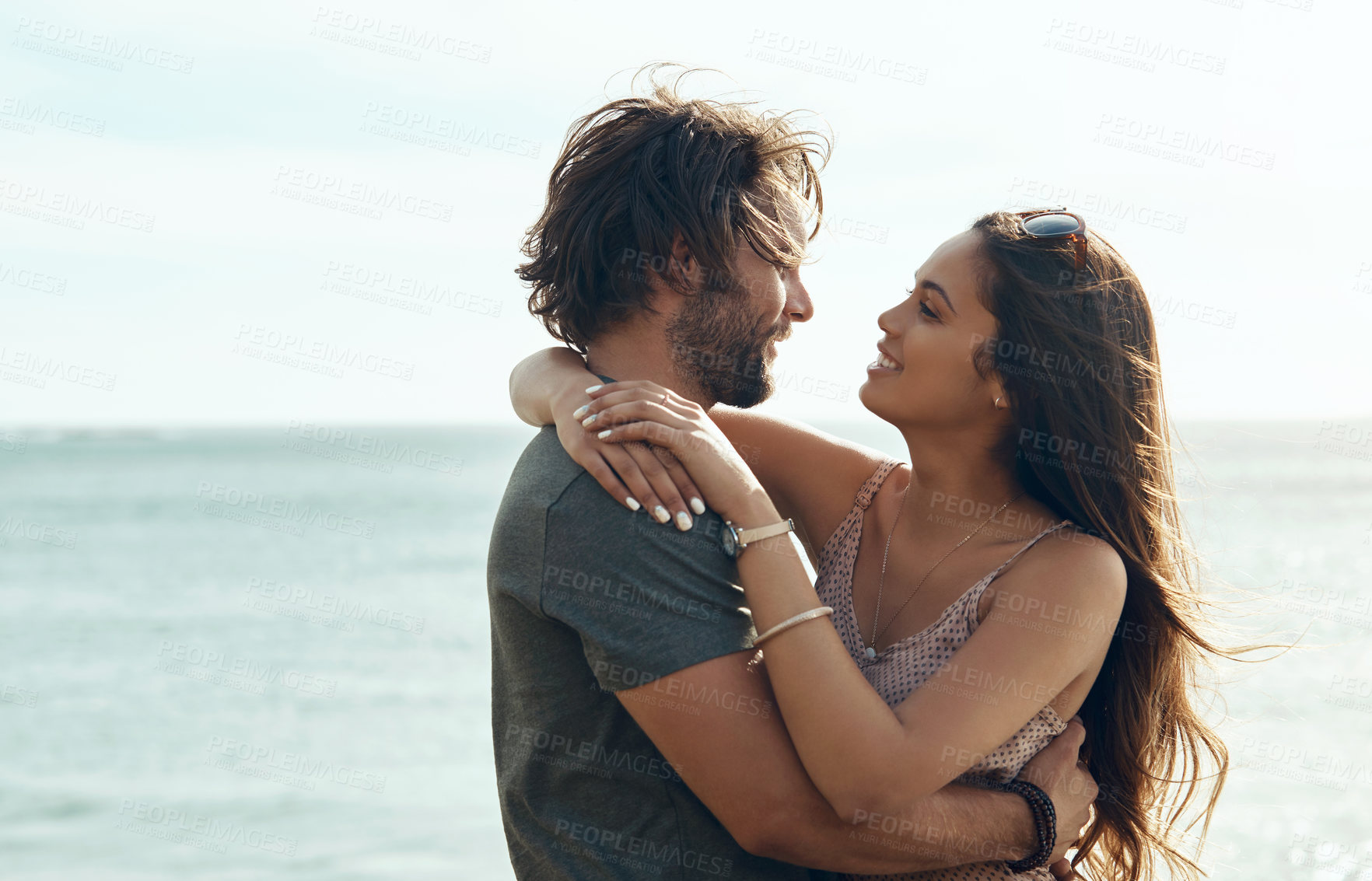 Buy stock photo Couple, beach and hug with love for holiday, weekend getaway or outdoor bonding together by seaside. Happy, man and woman with smile or embrace on ocean coast for romance, summer break or travel