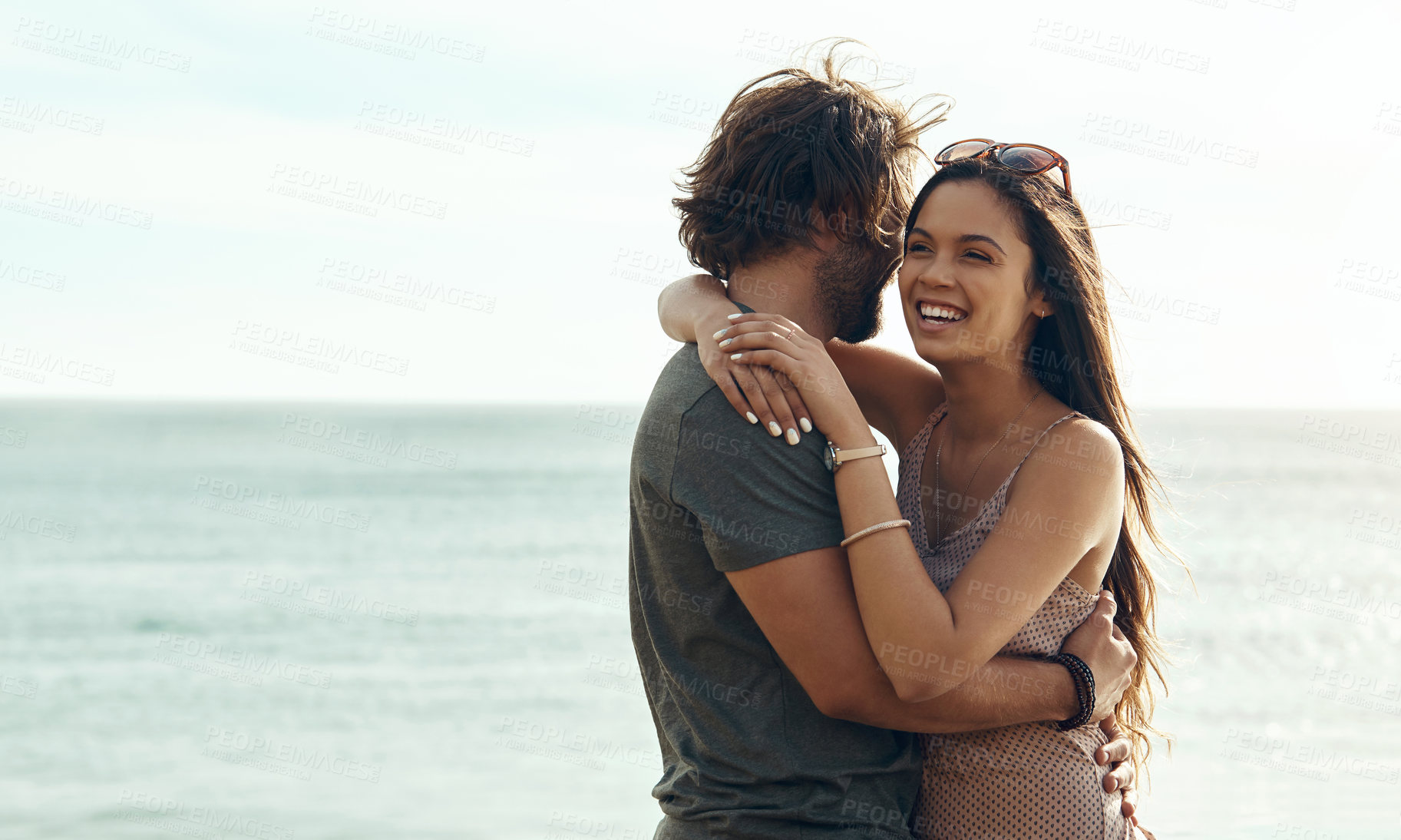 Buy stock photo Cropped shot of an affectionate young couple hugging each other while standing on the beach during a road trip