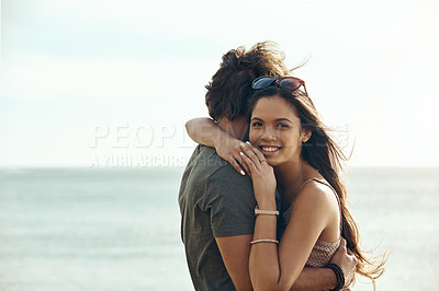Buy stock photo Cropped portrait of an affectionate young couple hugging each other while standing on the beach during a road trip