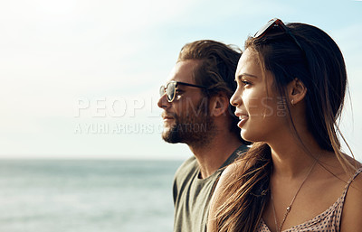 Buy stock photo Cropped shot of an affectionate young couple looking out at the ocean together during a road trip