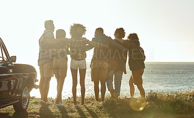Buy stock photo Full length rearview shot of a diverse young group of friends standing next to a car and facing the ocean