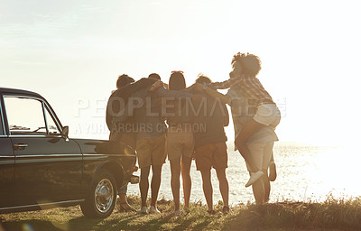 Buy stock photo Full length rearview shot of a diverse young group of friends standing next to a car and facing the ocean