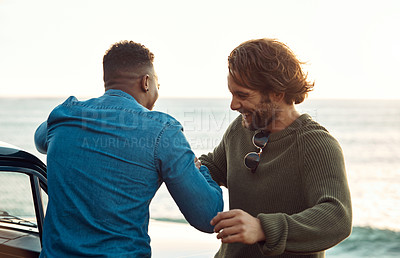 Buy stock photo Cropped shot of two handsome young men greeting each other at the beach during a road trip