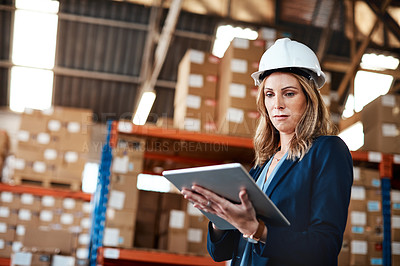 Buy stock photo Cropped shot of an attractive young businesswoman using a tablet while working in a warehouse