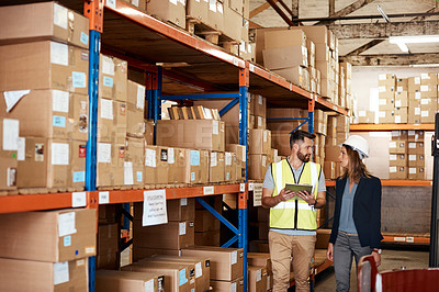 Buy stock photo Cropped shot of an attractive young businesswoman walking through a warehouse with a male worker