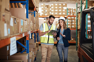 Buy stock photo Cropped shot of an attractive young businesswoman walking through a warehouse with a male worker