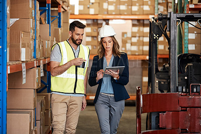Buy stock photo Cropped shot of an attractive young businesswoman walking through a warehouse with a male worker