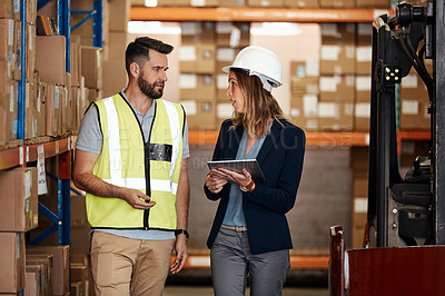 Buy stock photo Cropped shot of an attractive young businesswoman walking through a warehouse with a male worker