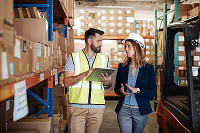 Buy stock photo Cropped shot of an attractive young businesswoman walking through a warehouse with a male worker