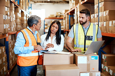 Buy stock photo Cropped shot of three warehouse workers checking on distribution logistics