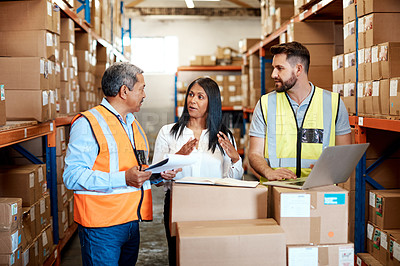 Buy stock photo Cropped shot of three warehouse workers checking on distribution logistics