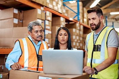 Buy stock photo Cropped shot of three warehouse workers checking on distribution logistics