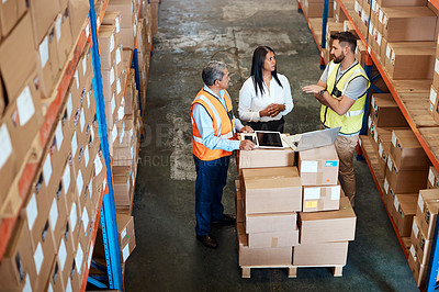Buy stock photo High angle shot of three warehouse workers checking on distribution logistics