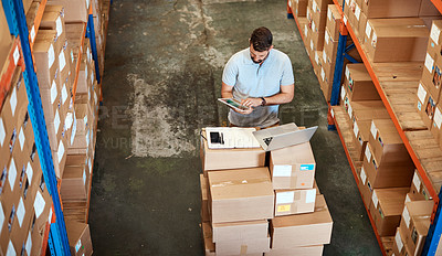 Buy stock photo High angle shot of a handsome young male warehouse worker working on a tablet
