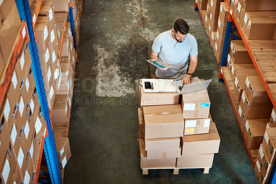 Buy stock photo High angle shot of a handsome young male warehouse worker working on a laptop