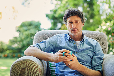 Buy stock photo Shot of a handsome mature man relaxing in a chair and drinking coffee in his backyard