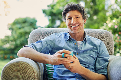 Buy stock photo Shot of a handsome mature man relaxing in a chair and drinking coffee in his backyard
