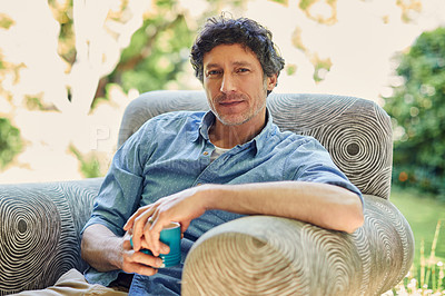 Buy stock photo Shot of a handsome mature man relaxing in a chair and drinking coffee in his backyard