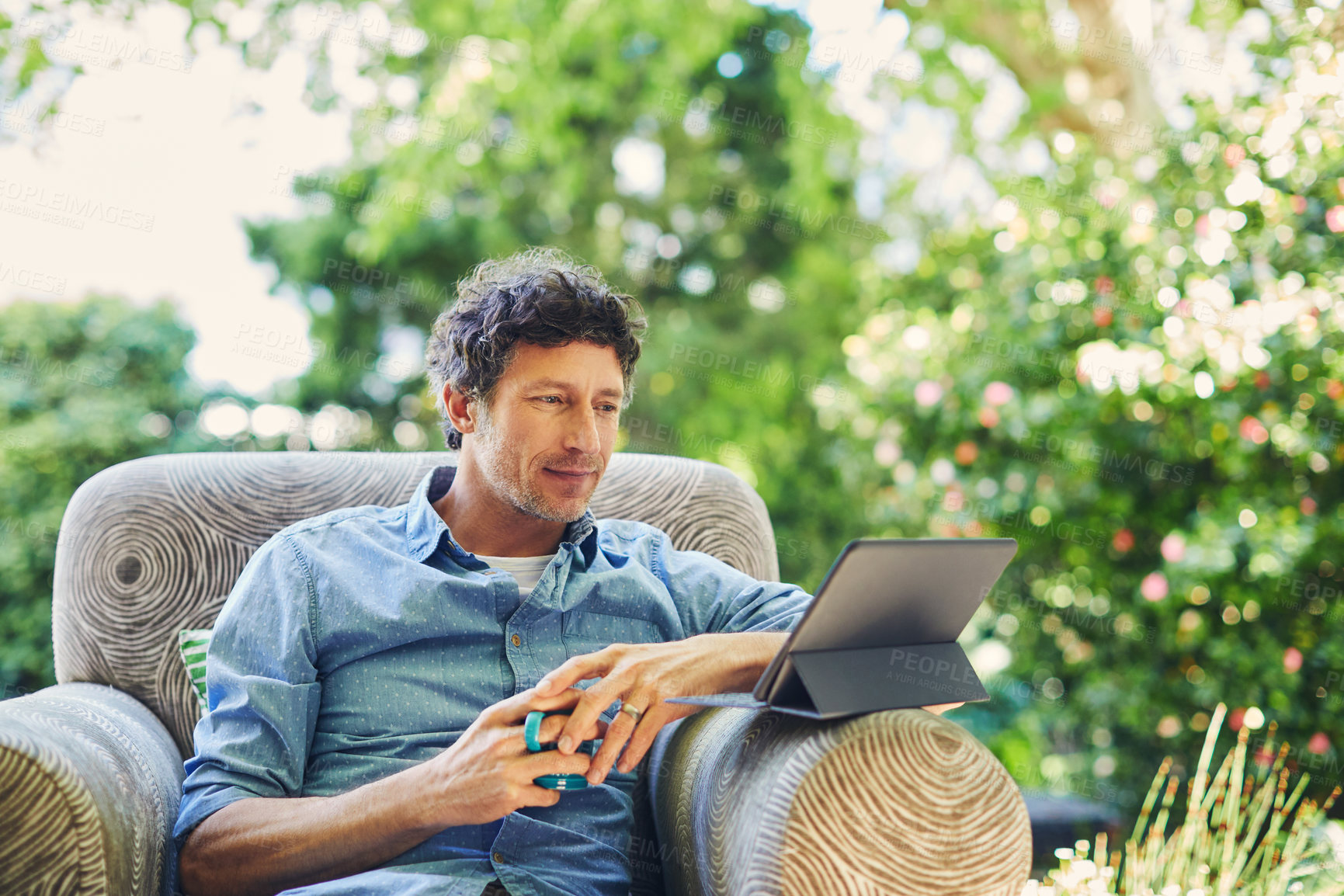 Buy stock photo Man, rest and coffee in backyard with tablet, internet connectivity and digital app to watch movie. Mature person, relax outdoor and streaming show on couch with tech, tea and online entertainment.